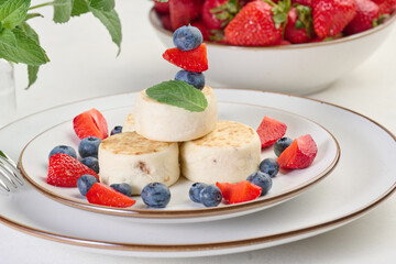 Stack of four cheesecakes on a plate with berries, blueberries, strawberries and cherries.