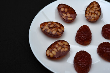 Marmalade in the form of forest cones. Marmalade with pine nuts on a white plate.