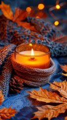Cozy Autumn Candle Lit with Fall Leaves and Knitted Scarf in a Warm Setting
