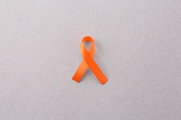 Orange awareness ribbon on gray background, top view