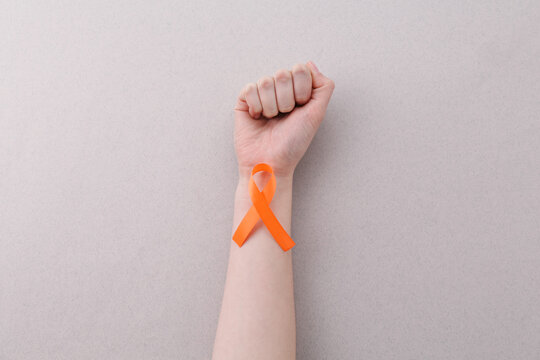 Woman with orange awareness ribbon on gray background, top view