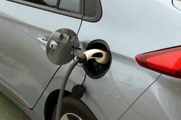 Modern electric car charging from station outdoors