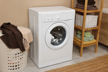 Washing machine, basket and shelving unit near beige wall indoors