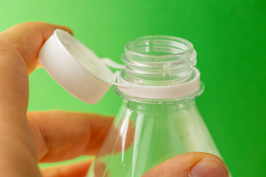 Plastic bottle with a new cap for mineral water. Concept. EU Directive on environmental protection, Green background, close up