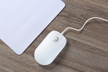 Computer mouse with mousepad on wooden desk, top view