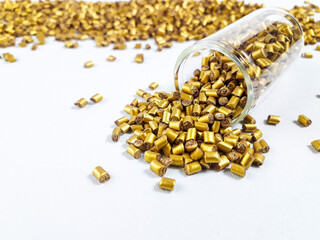 Gold color masterbatch granules with glass tube on white background.Color pigment carrier polymer in plastic industry