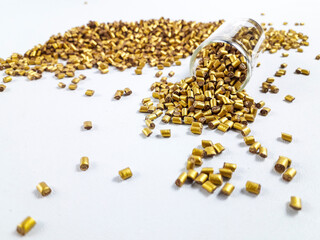 Gold color masterbatch granules with glass tube on white background.Color pigment carrier polymer...