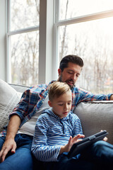 Man, son and tablet on couch with internet for educational gaming, movie bonding and online tv...