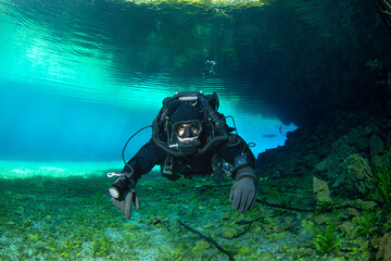 A diver using a rebreather is diving in a crystal clear water