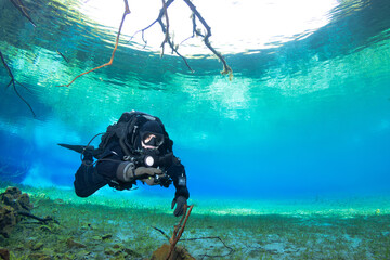 A diver using a rebreather is diving in a crystal clear water