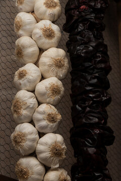 String of garlic and dried red pepper hanging on a grid.