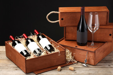 Boxes with wine bottles and glass on wooden table against black background