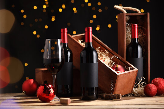 Bottles of wine, glass, wooden boxes, corkscrew and red Christmas balls on table