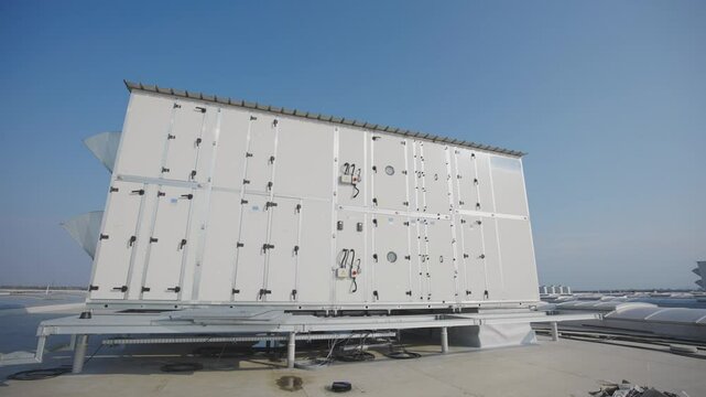 Slide and pan shot of big box with air handling unit located on building flat roof. Preparing connection and commissioning.