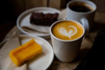 Coffee break. Two mugs of American and latte art on a wooden background. Chocolate brownie and yuzu cake slices. Delicious sweet food and coffees. Flat white, latte. Food and drink.
