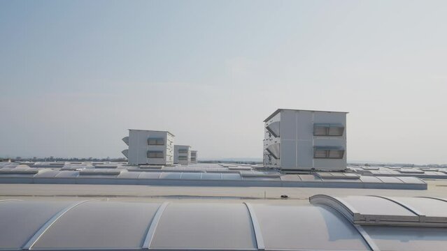 Building roof with rows of skylights and massive air handling units. Flat roof of large industrial hall.