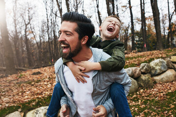 Nature, piggyback and father with boy in forest for game, fun and bonding together. Park, playing and happy man with excited child on back for support, weekend trip or autumn weather in Washington
