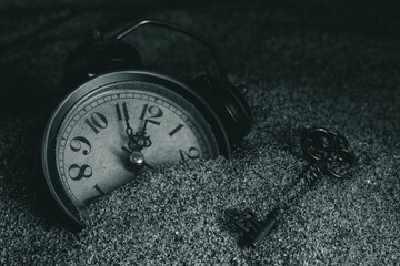 Vintage alarm clock in the sand. Selective focus. Toned.