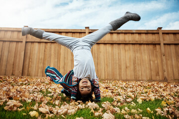Child, playing and cartwheels in outdoor, autumn and cheerful for growth, fun and development. Happy kid, girl and activity for joy, energy and skills as preschooler in backyard, garden or park field
