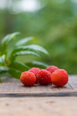 Arbutus berries or Red Yangmei fruit on the wood, Red Bayberry, Yumberry, Yamamomo, Waxberry on white with work path.