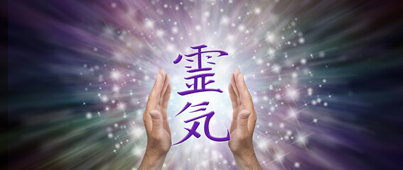 Reiki Healer with the Reiki Kanji Symbol - male hands around a purple Kanji symbol against a dark radiating sparkling background with space for a spiritual message 
