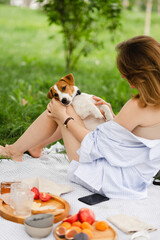 Caucasian happy woman relaxing on summer picnic with Jack Russell Terrier dog. Young woman rest...