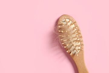 Wooden brush with lost hair on pink background, top view. Space for text