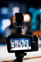 Focus on professional camera capturing footage of online star in blurry background filming tutorial on how to do smartphone maintenance, teaching viewers about fixing broken mobile phone