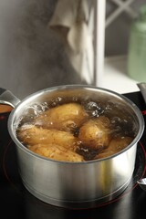 Boiling potatoes in saucepan on stove in kitchen