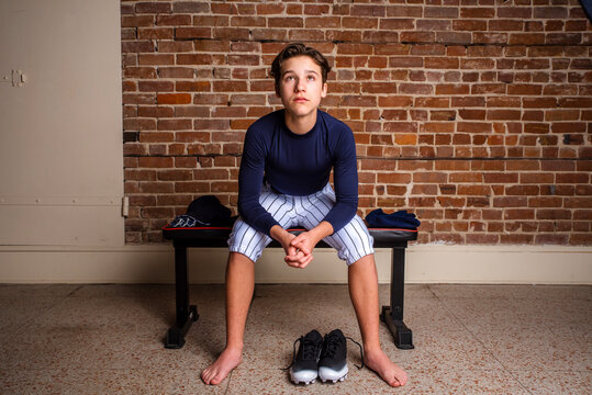 Young teen baseball player sitting on a bench intently listening to his coach before a game