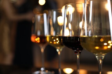 Different tasty wines in glasses indoors, selective focus