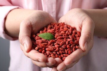 Woman holding pile of dried goji berries, closeup