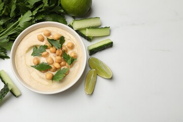 Tasty hummus with chickpeas in bowl and fresh products on light table, flat lay. Space for text