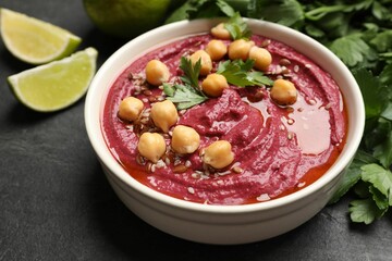 Tasty beet hummus with chickpeas and parsley in bowl on grey textured table, closeup