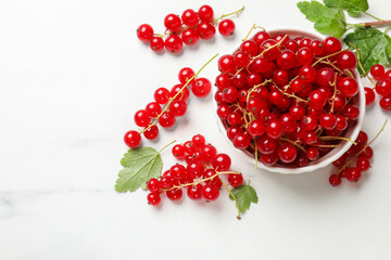 Fresh red currant berries in bowl on white table, top view. Space for text