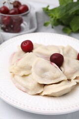 Traditional Ukrainian dumplings (varenyky) with cherries served on white table, closeup
