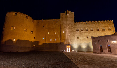 Jabreen citadel fortress stone walls and round bastion tower in night illumination, Bahla,...