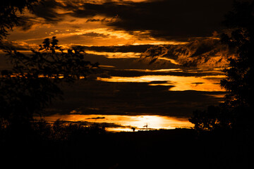 An awe-inspiring sunset with a fiery sky bursting with intense colors of red, orange, and yellow....