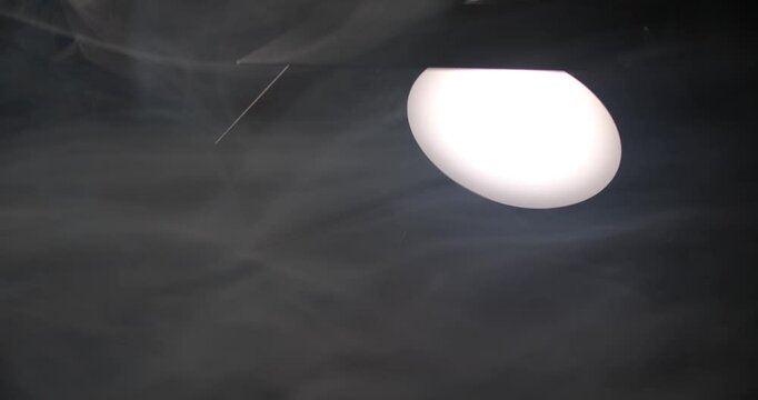 Switching on the lighting equipment in the studio against the background of smoke.
