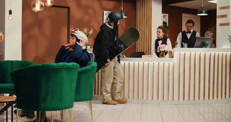 Upon arrival, staff member welcomed tourist at reception desk and assistant escorted customer with their baggage. Skier delighted to hit the slopes at premium ski lodge. Handheld shot.