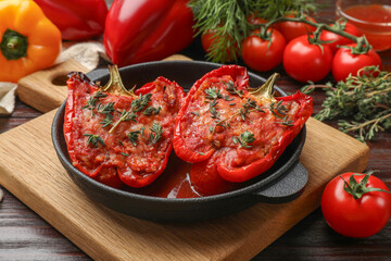 Tasty stuffed peppers in dish on wooden table