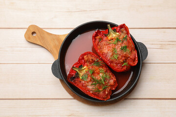 Tasty stuffed peppers in dish on white wooden table, top view