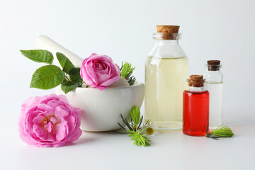 Aromatherapy. Different essential oils, flowers, mortar, pestle and fir twigs on white background