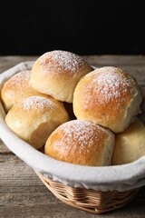 Delicious dough balls in basket on wooden table, closeup