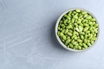 Fresh edamame soybeans in bowl on grey textured table, top view. Space for text