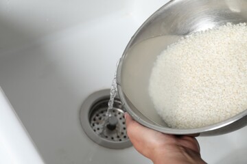 Woman rinsing rice in bowl above sink, closeup. Space for text