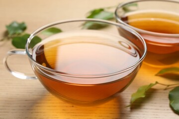 Refreshing green tea in cups and leaves on wooden table, closeup