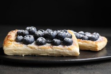 Tasty puff pastries with blueberries on grey table, closeup