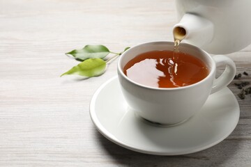 Pouring refreshing green tea into cup at grey wooden table, closeup. Space for text