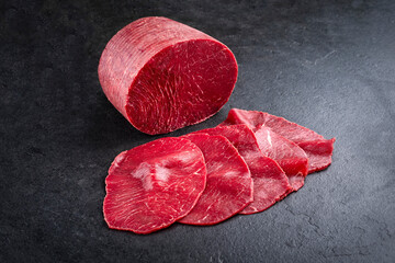 Traditionelle Carpaccio Scheiben und am Stück vom Rind angeboten mit Kräutern als Nahaufnahme auf...